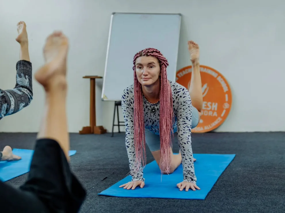 Student practising on the mat in the yoga hall at Rishikesh Yog Kendra