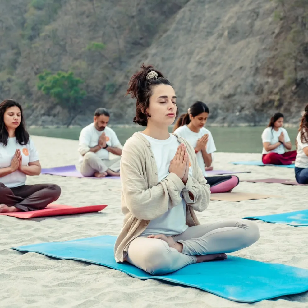 Students meditating together on the river bank in Rishikesh