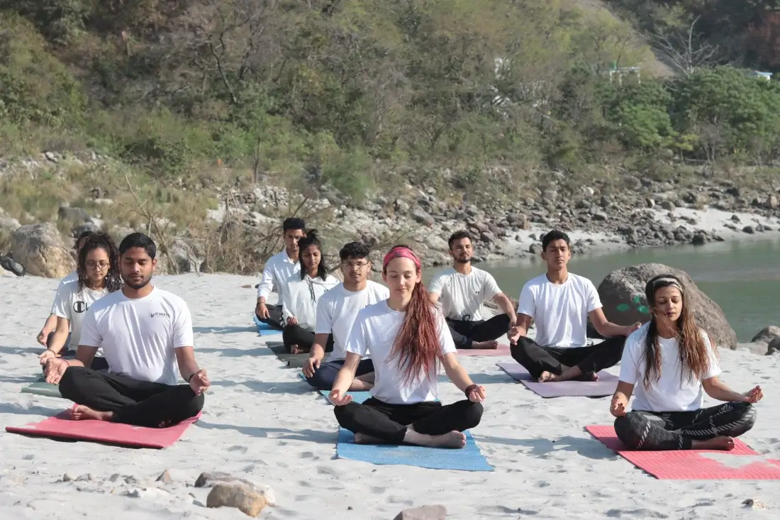 200 hour YTTC students seated in meditation on the banks of the Ganga