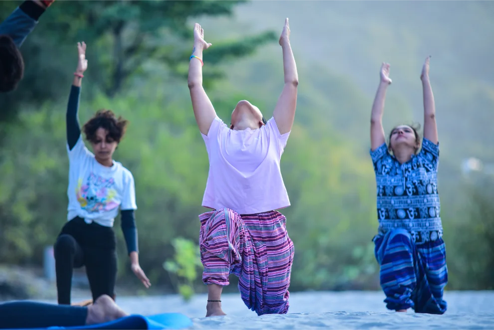 Small group practising a kneeling backbend during a morning outdoor class