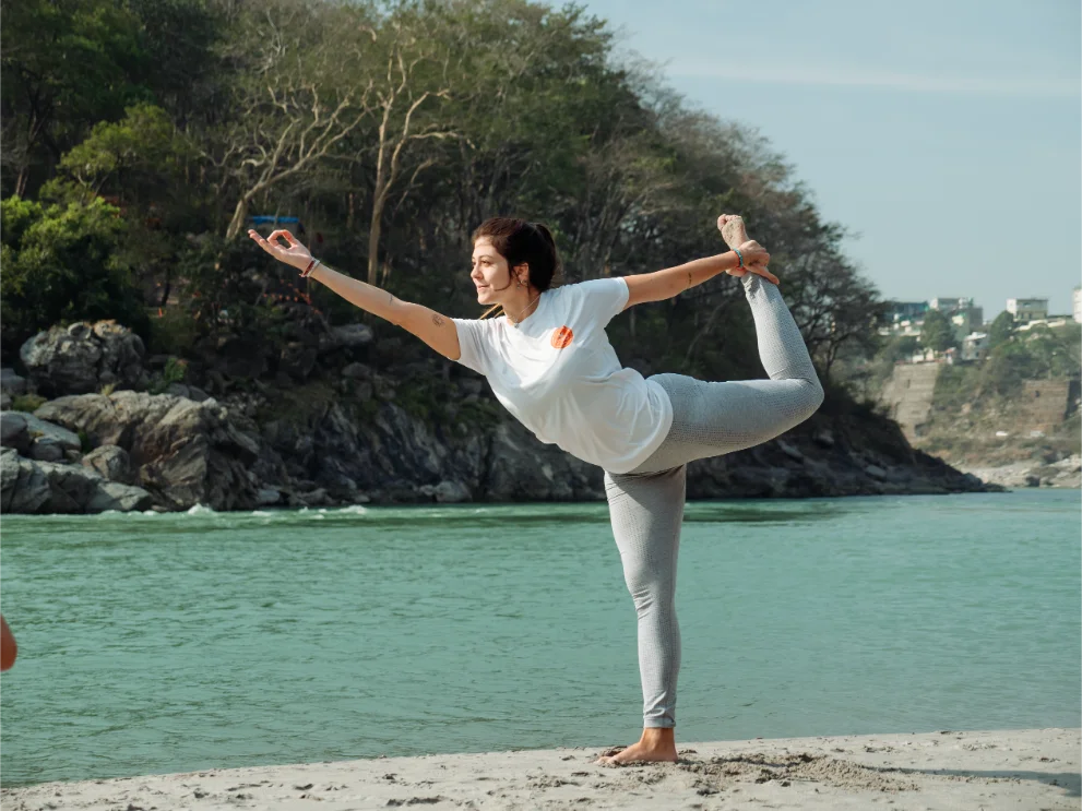 Student in dancer pose on the banks of the Ganga in Rishikesh