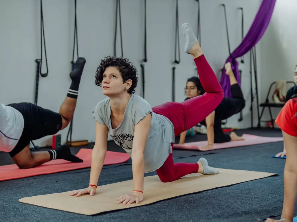 Students practising balancing table pose in the yoga hall at Rishikesh Yog Kendra