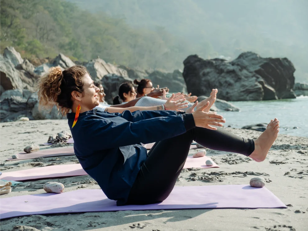Students holding boat pose during a riverside class in Rishikesh
