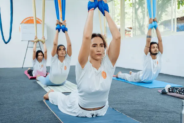 Teacher leading a seated hammock stretch while the group follows behind her