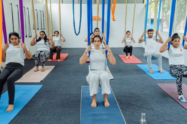 A led aerial yoga class seated in the hammocks during the 50 hour teacher training in Rishikesh