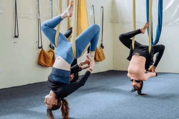 Two students holding supported inversions in the aerial hammock