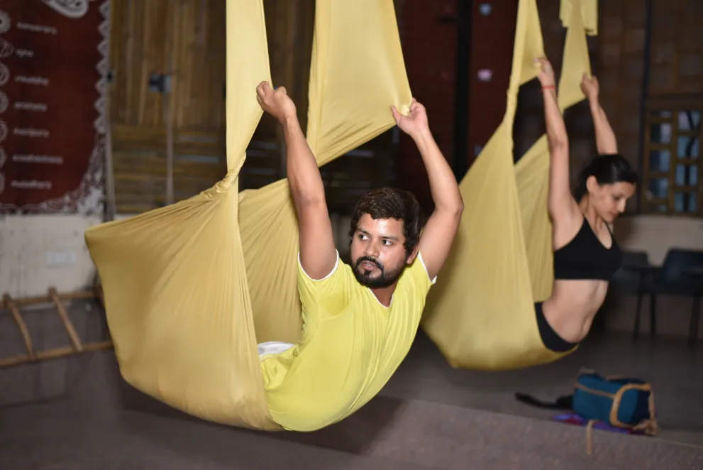 Two students practising side by side in the hammocks during a group session