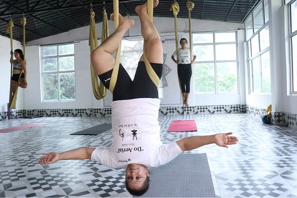 Student suspended upside down in the hammock with arms open wide