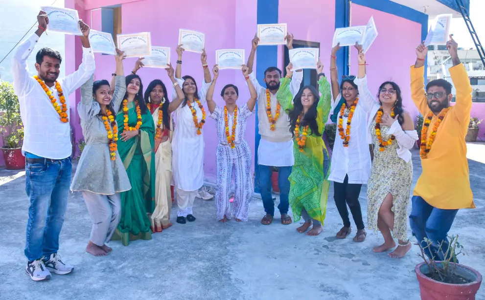 The full group standing together with their certificates held above their heads on the campus terrace