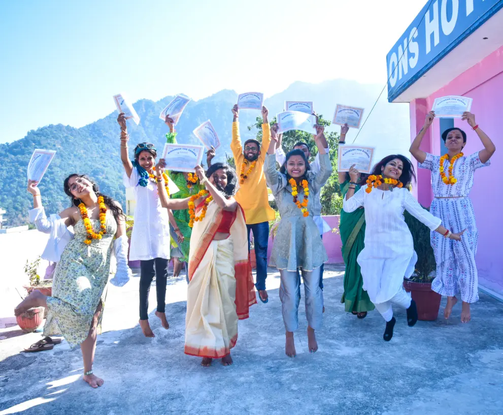 Graduating students leaping with their certificates raised on the campus terrace, the Himalayan foothills behind them