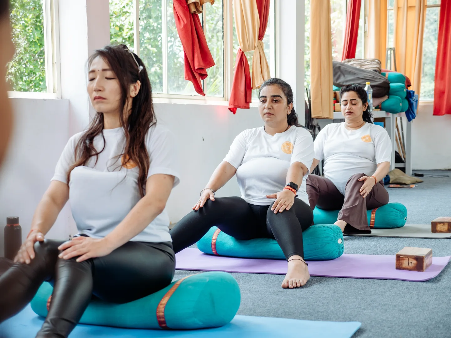Prenatal yoga students seated on bolsters for a guided breathing practice