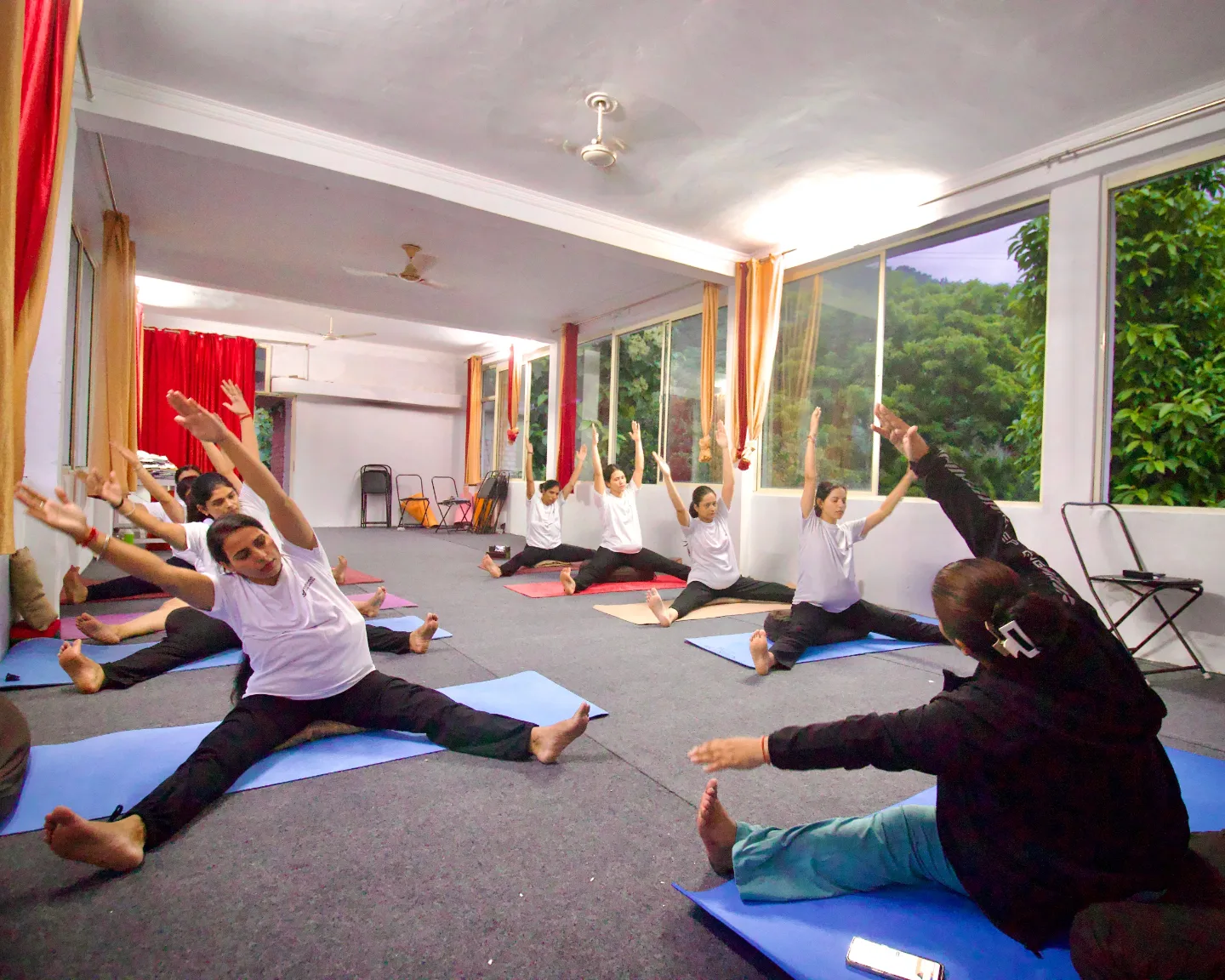 The whole group practising a seated wide-legged stretch together in an evening class