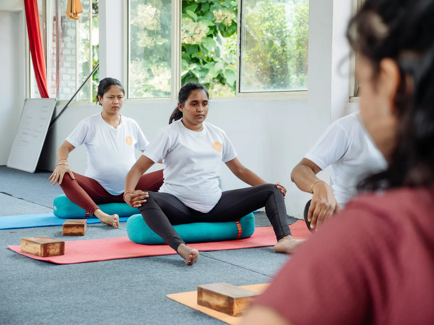 Teacher working with a small group of expecting mothers seated on bolsters