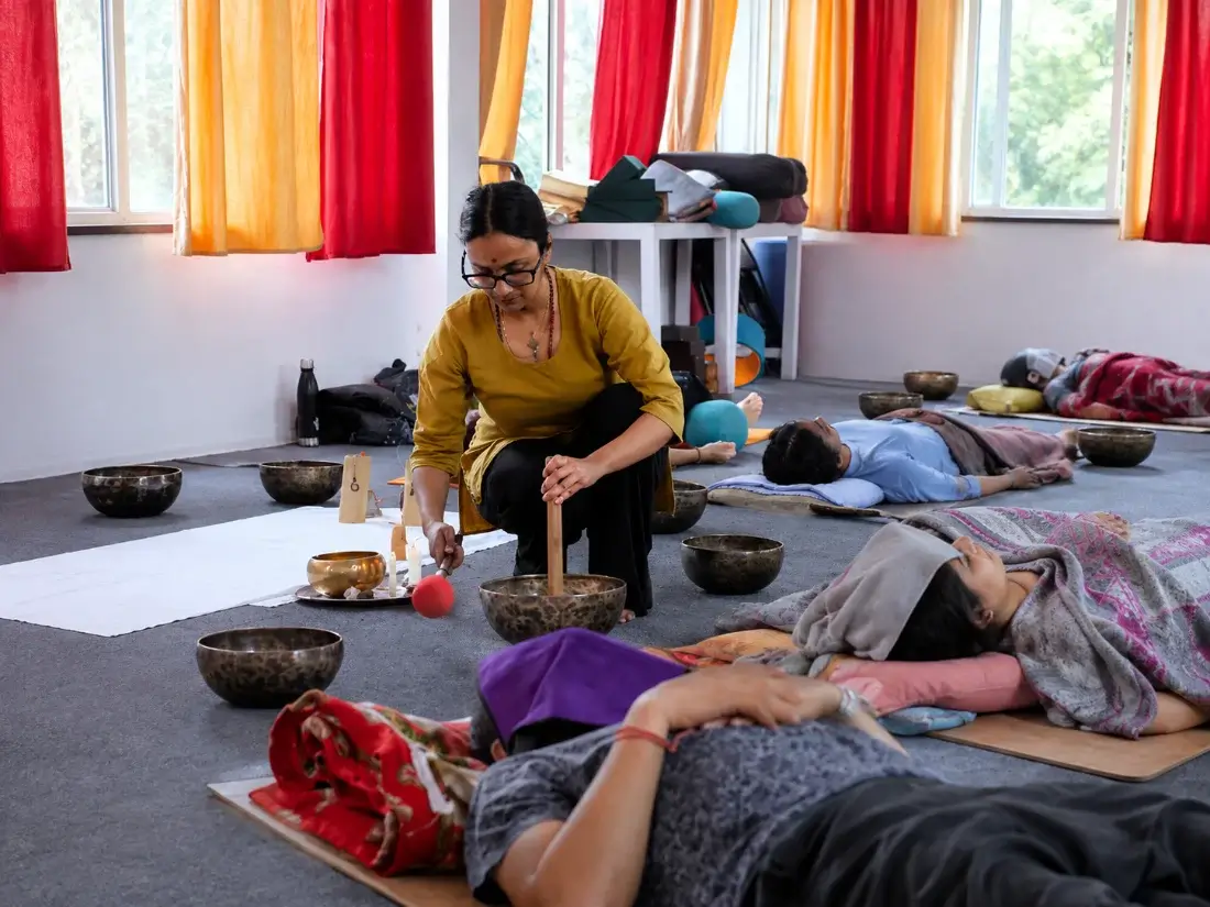 Teacher demonstrating bowl technique to students lying blanketed and eye-covered during training