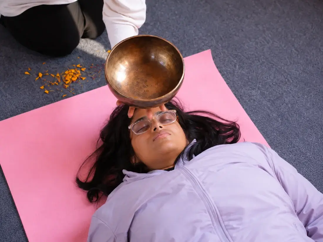 Singing bowl rested on a student&rsquo;s forehead during a sound therapy treatment