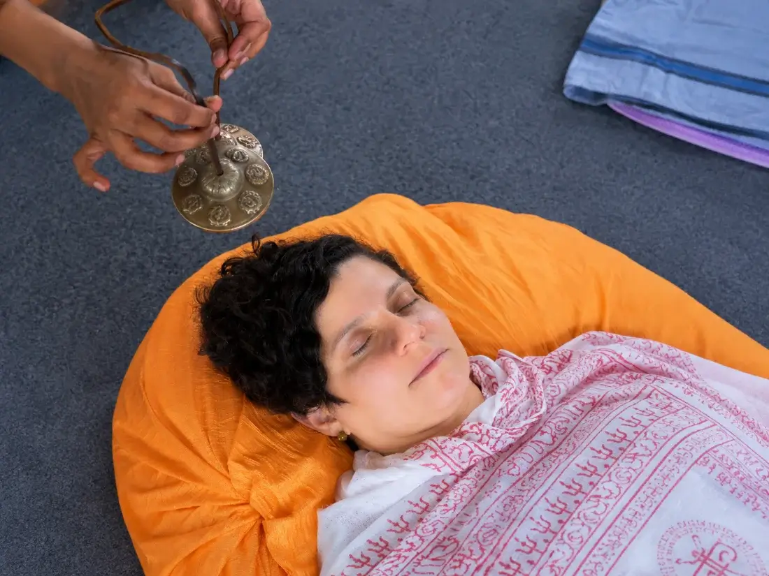 Close view of tingsha cymbals chimed beside a resting student&rsquo;s head