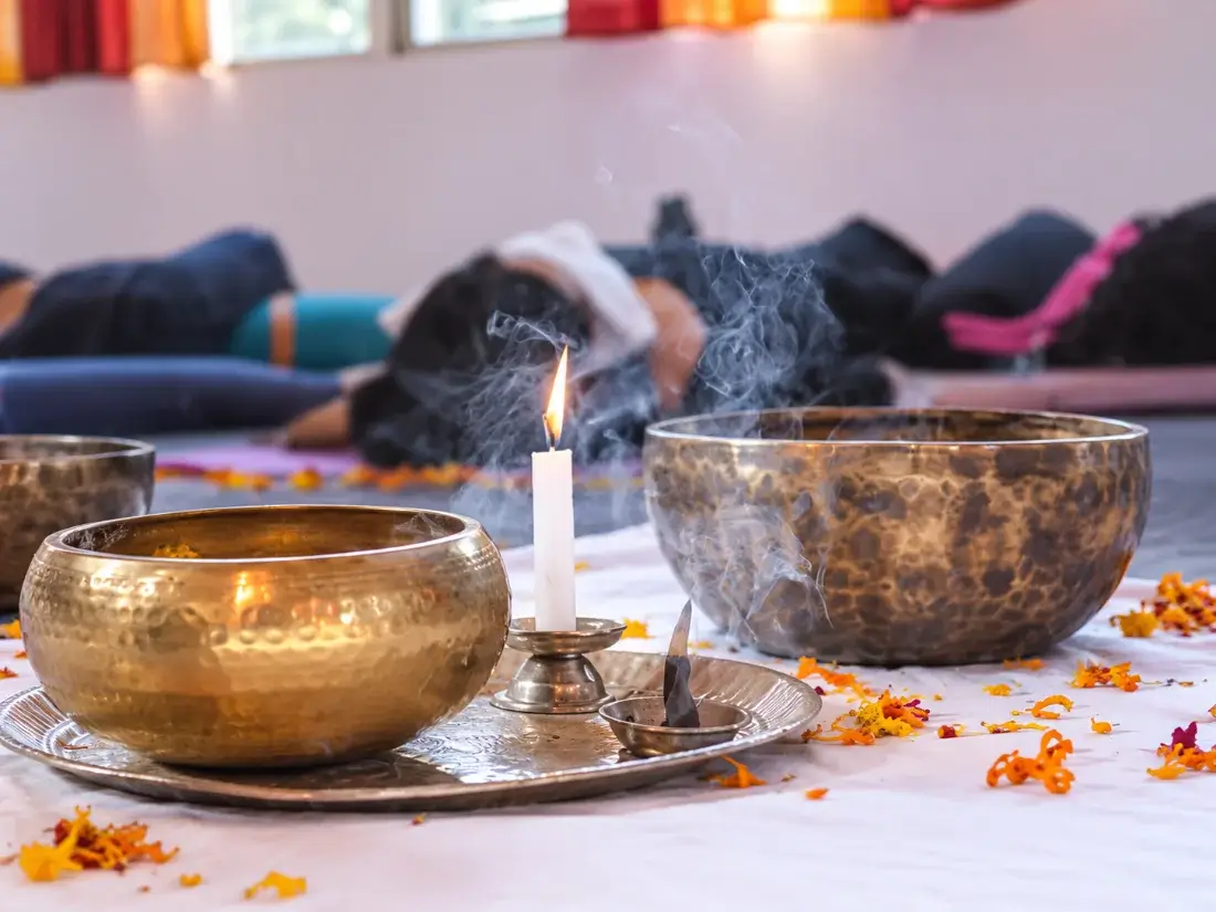Bowls, a lit candle and incense set out as a session space is prepared