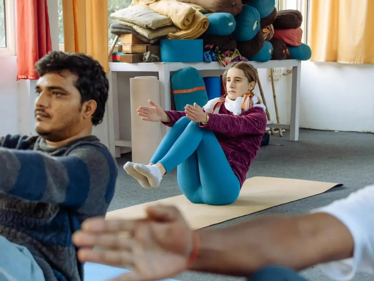 Students practising a seated pose together in the studio with bolsters and props to hand